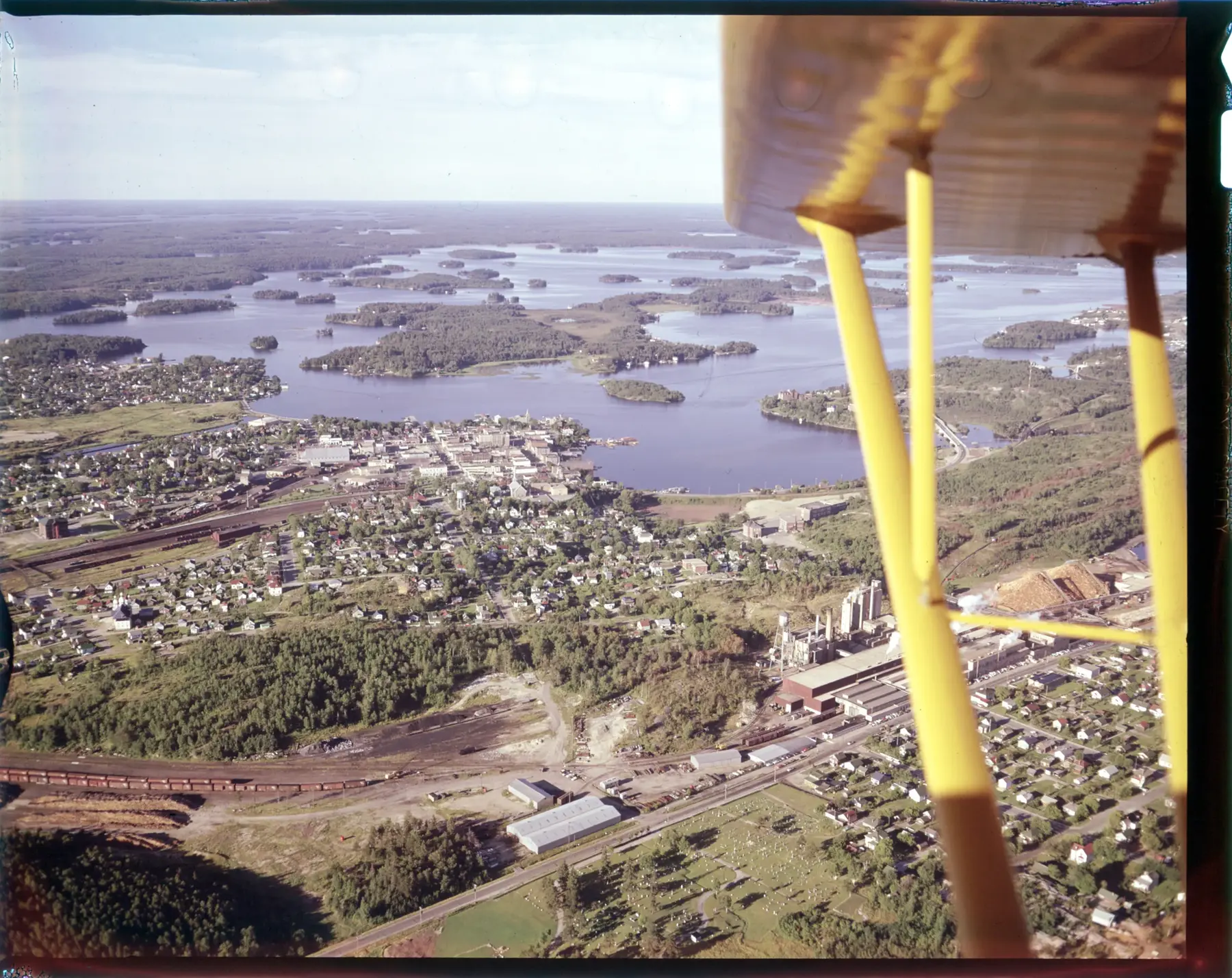 Kenora and the Lake of the Woods from a floatplane, its yellow float struts in the frame